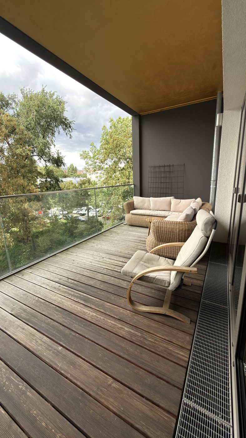 Balkon mit Lounge-Sofa und Blick auf Bäume und Park