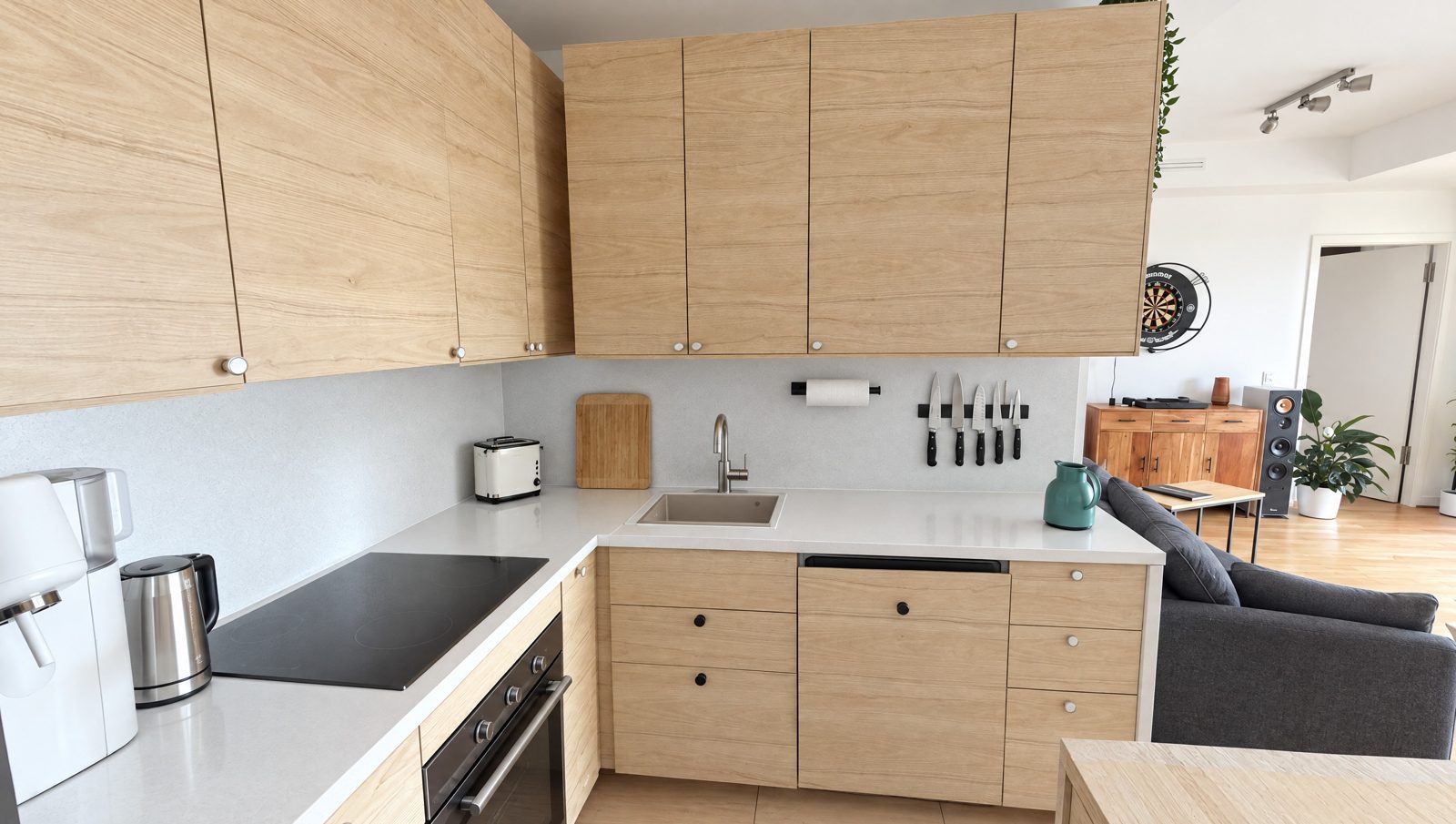 Küche mit Holzfronten, Kochfeld und Blick ins Wohnzimmer