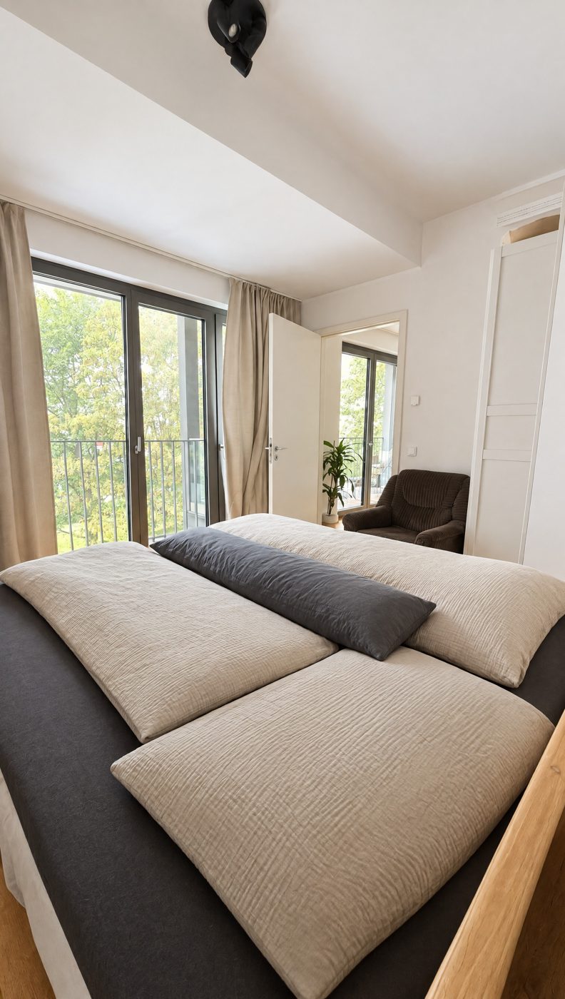 Schlafzimmer mit frisch gemachtem Bett und Blick ins Grüne